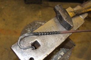 Young demonstrated blacksmithing processes by creating a decorative hook.