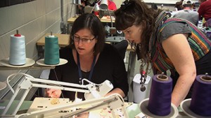 Two sewing students examining project.