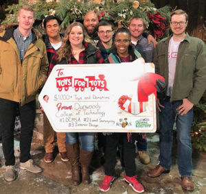 Photo of a group of students on the WCCO-TV set holding a large Toys for Tots donation tag.