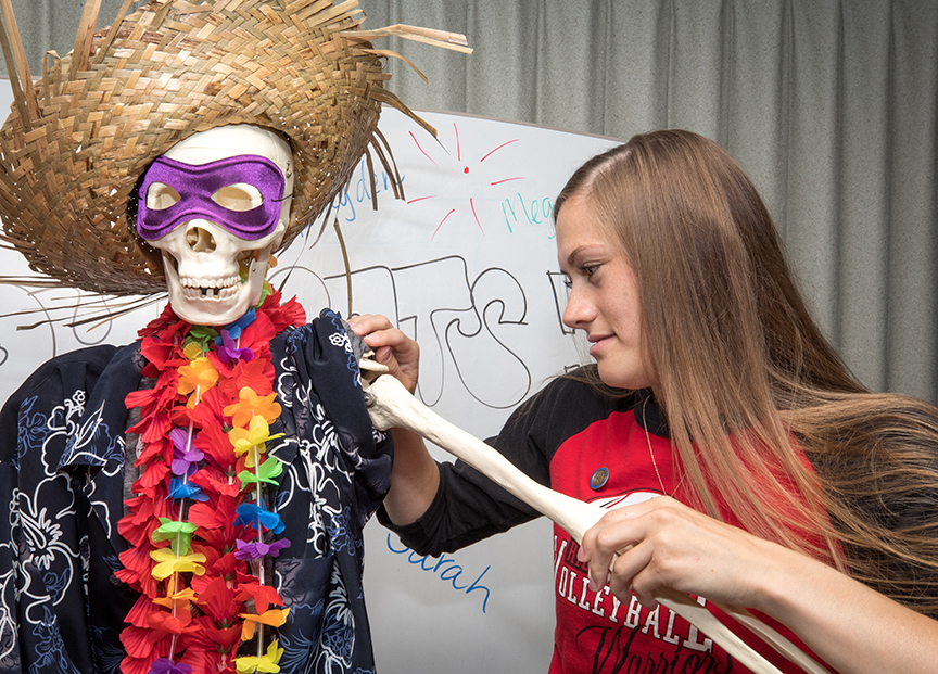 Amber Skelton fixes the arm of Mr. Bones during a class celebration.