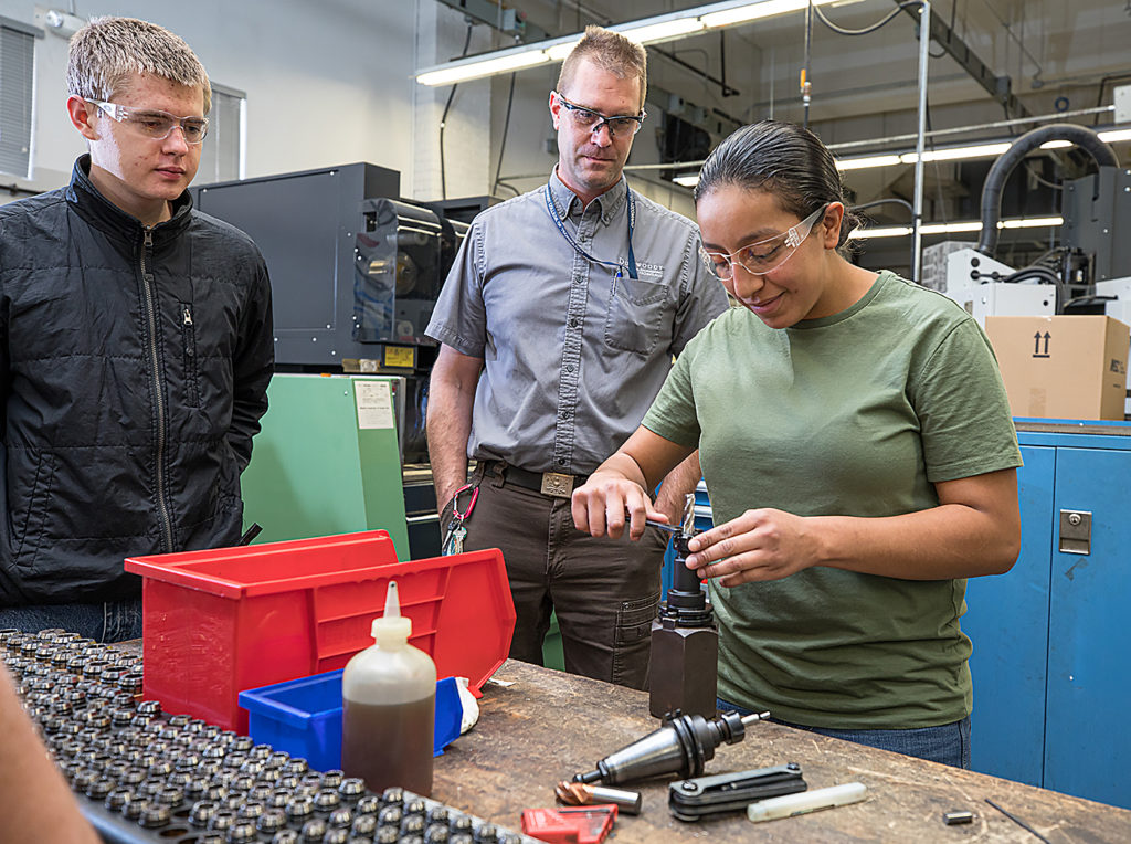 Liz Rivas, right, with her instructor and classmates learn about CNC machines during lab.