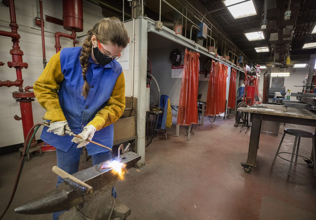 Becs Wells heats a metal leaf to personalize it for the Graduation tree