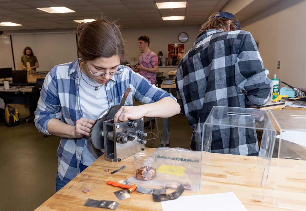 Bridgette Dalldorf works on a penny press she and her team members built.