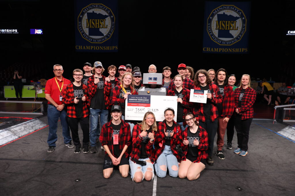 The WarroadFIRST Robotics team posing with their mentors, a giant check (meant to symbolize their $500 award from Dunwoody), and Dean E.J. Daigle
