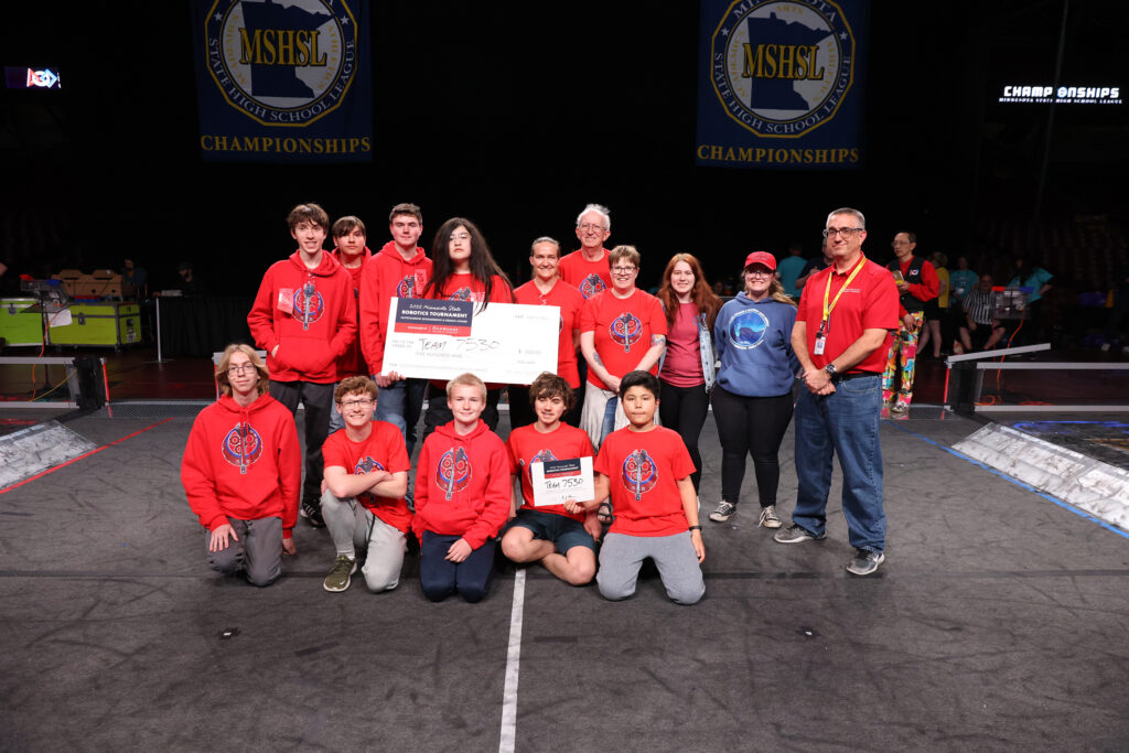 The Watertown Mayer FIRST Robotics team posing with their mentors, a giant check (meant to symbolize their $500 award from Dunwoody), and Dean E.J. Daigle