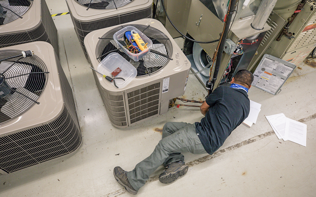 Student works on heating and cooling equipment in a lab.