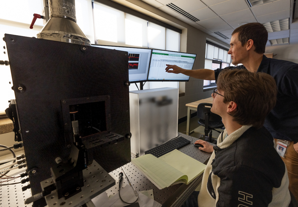 photo of student conducting research on ammonia combustion flame with faculty.