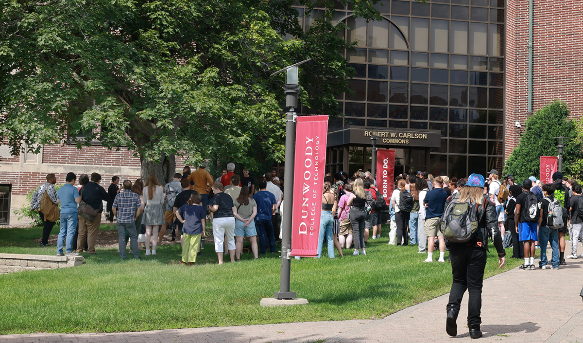 a large group of students under a tree and outside a building.