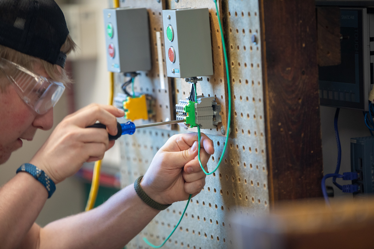 Electrical student works on wiring a project in a commercial electrical lab.