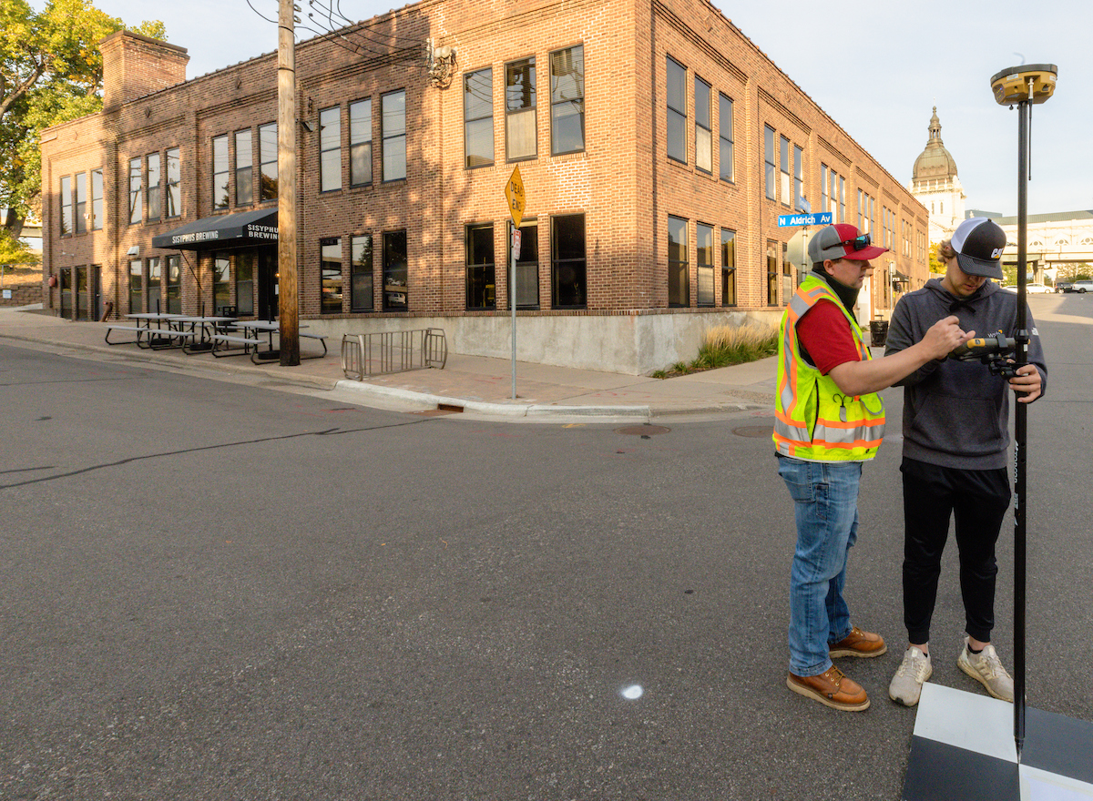 Land surveying student Dan Fjell works with surveying equipment outside.