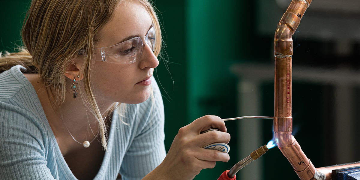 A female student using an HVAC torch