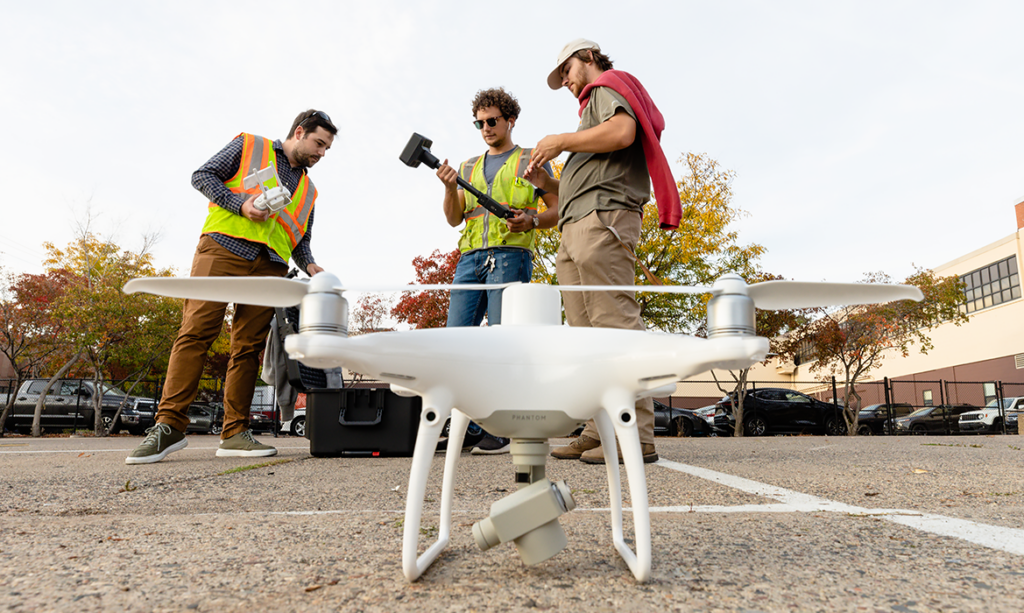 Students in the associate in surveying and civil engineering technology program standing next to a drone or an unmanned aerial vehicle.