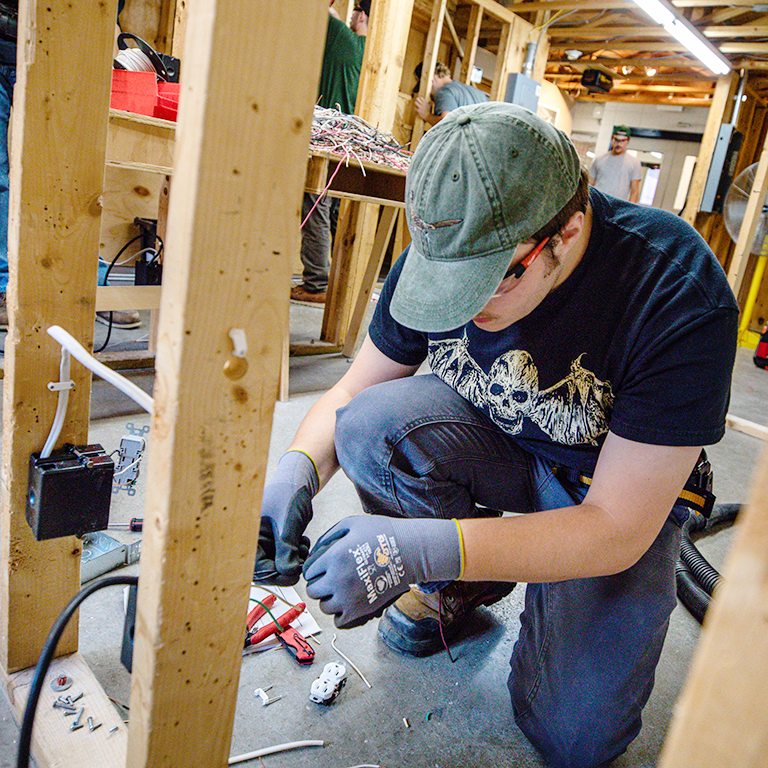 Student in the Electrical Construction and Maintenance program wire an outlet in the three-story house, a lab inside Dunwoody.