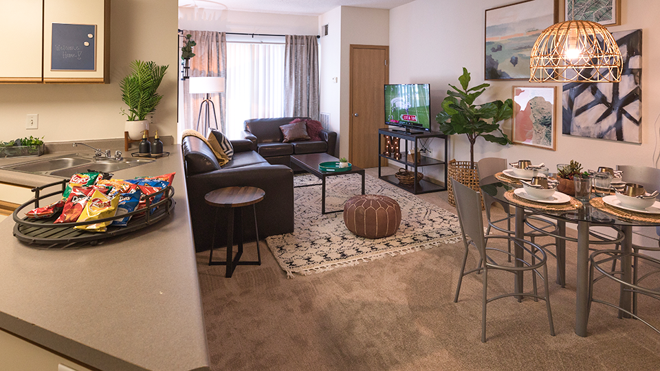 Living room area at the Quad with kitchen counter, dining table, couch, and more