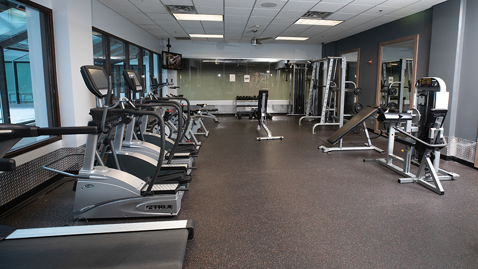 A large work out room with treadmills, weights, and other work out equipment