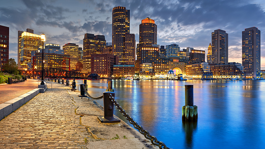 A photo of a city at dusk with tall buildings with lots of lights on inside